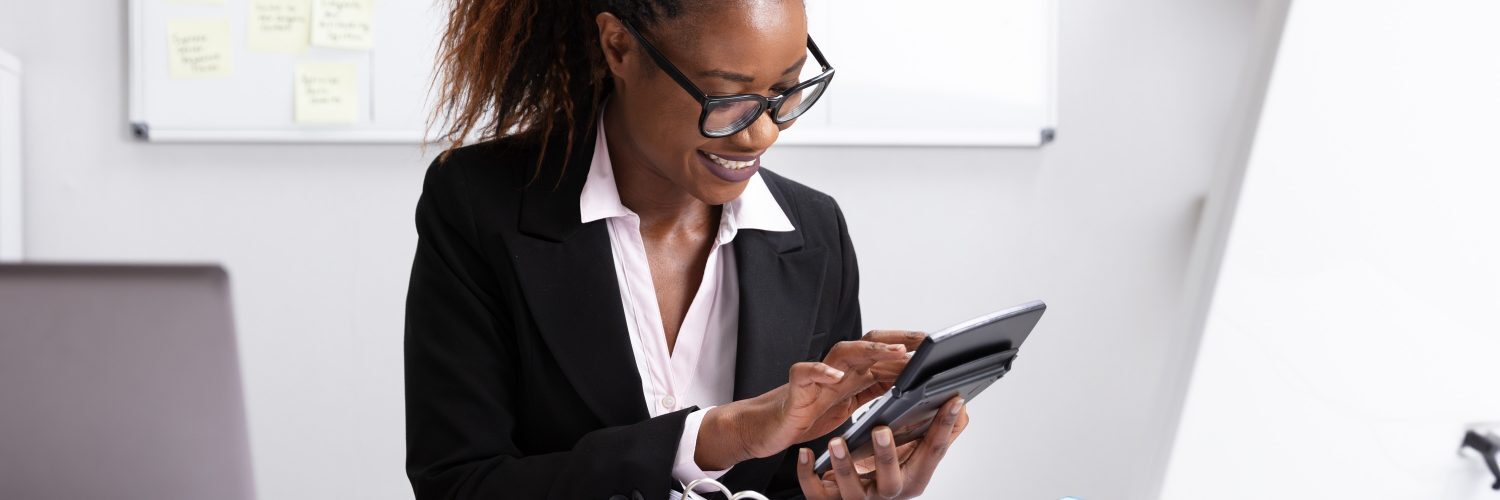 A professional woman in a business suit is focused on her tablet, engaged in work or research.