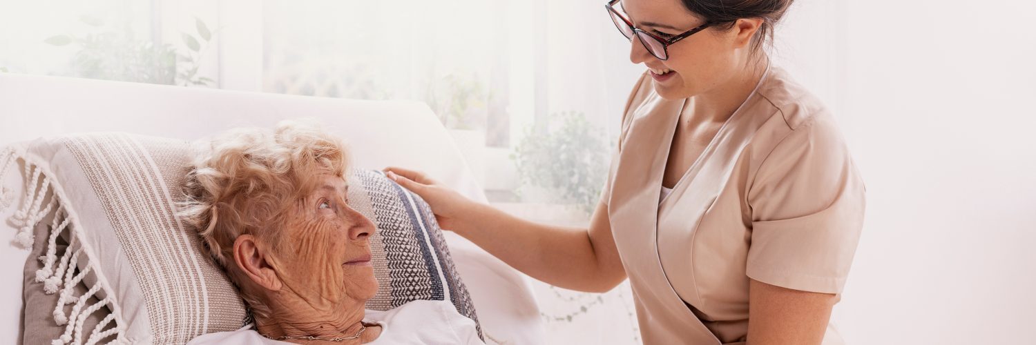 A caring nurse assisting an elderly woman in bed, providing compassionate care and support.