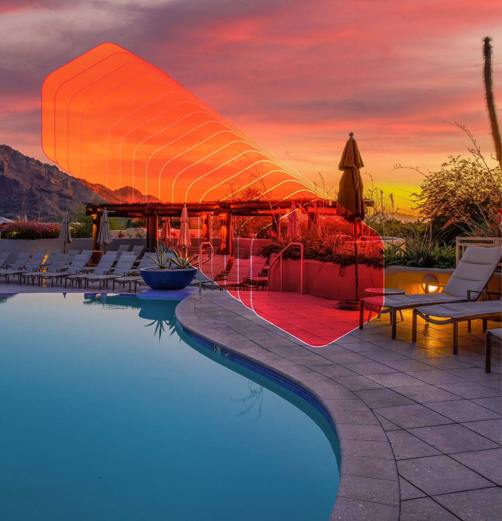 A serene pool with comfortable lounge chairs and a breathtaking sunset in the background.